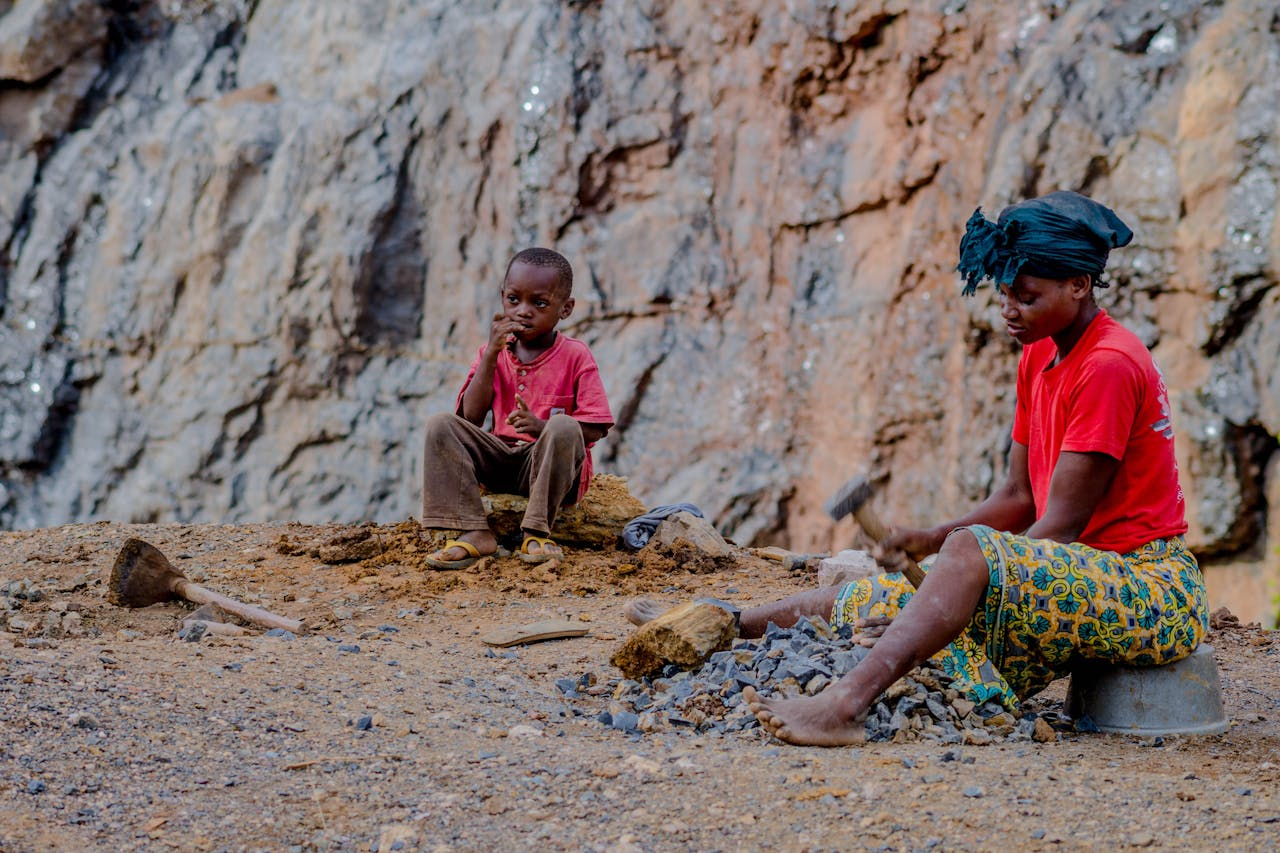 about-01 A mother and child in a rural setting mining stones together.